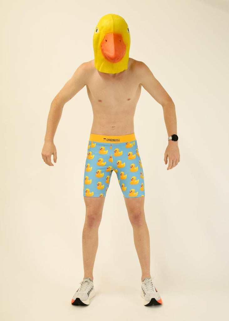 Model wearing Chicknlegs men's 8 inch half tights in the rubber ducky design posing with a yellow duck mask.