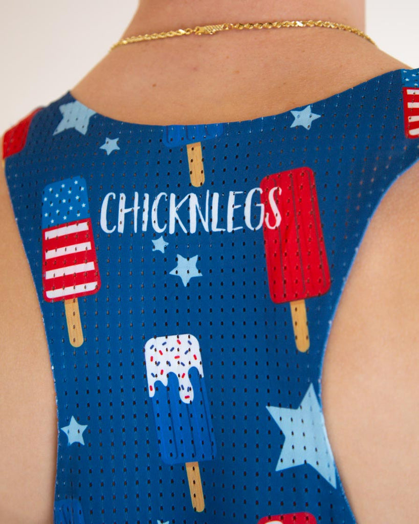 Runner is wearing ChicknLegs men's performance singlet in the USA Popsicle design, facing front. The print has red, white and blue ice cream on it with stars, a close up of the singlet is shown for the logo.