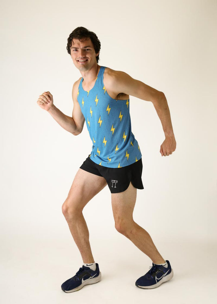 Model wearing Chicknlegs men's peformance singlet in blue bolts design in a fun running pose.