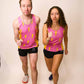 Runners wearing the men's and women's pink bolts performance singlets striking a running pose.