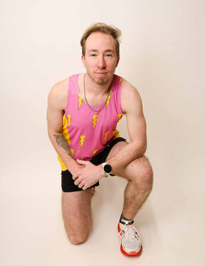 Runner kneeling while wearing the pink bolts performance singlet.