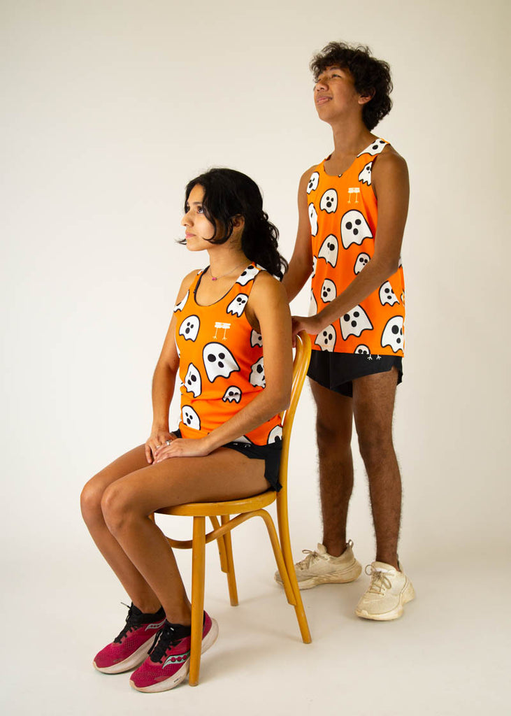 The model is a runner wearing chicknlegs women's runners singlet in the ghost design, facing front while posing with another model who is a runner and wearing the men's ghost singlet looking up in the air.