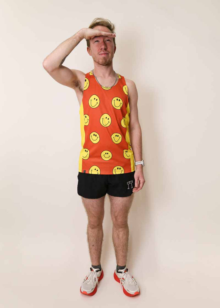 Runner shielding his eyes from the sun while wearing the men's smiley face performance singlet.