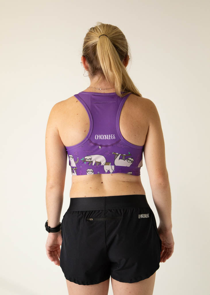 The model is a runner who is wearing Chicknlegs OG sports bra, in the sloth design, facing away from the camera to show the back of the sports bra. A pocket is included.