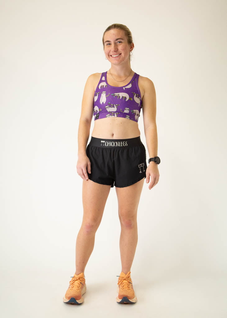 The model is a runner who is wearing Chicknlegs OG sports bra, in the sloth design, facing front in a standing pose.