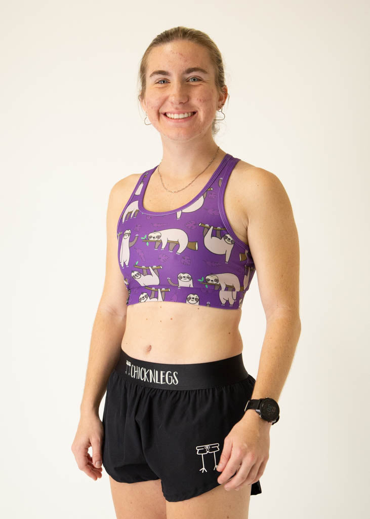 The model is a runner who is wearing Chicknlegs OG sports bra, in the sloth design, facing left.