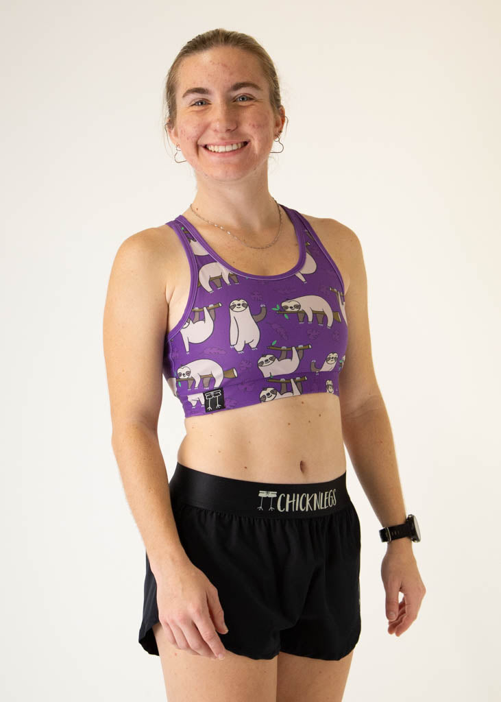 The model is a runner who is wearing Chicknlegs OG sports bra, in the sloth design, facing right.