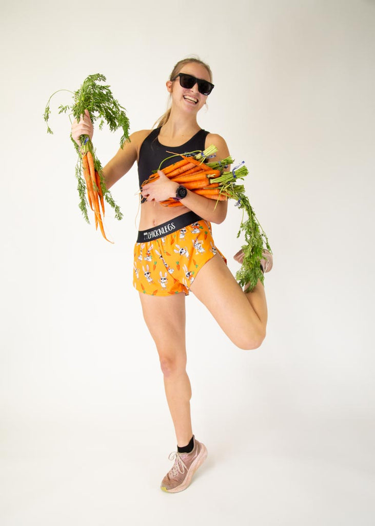 Runner is wearing ChicknLegs in the women's 1.5 in split running shorts with the bad bunny design. The print has white rabbits on it with sunglasses and carrots, posing with sunglasses and real carrots.