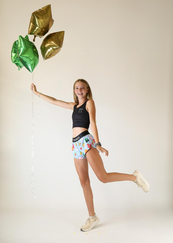 Runner posing with balloons while wearing the ChicknLegs Women's 1.5 inch Charms running shorts.