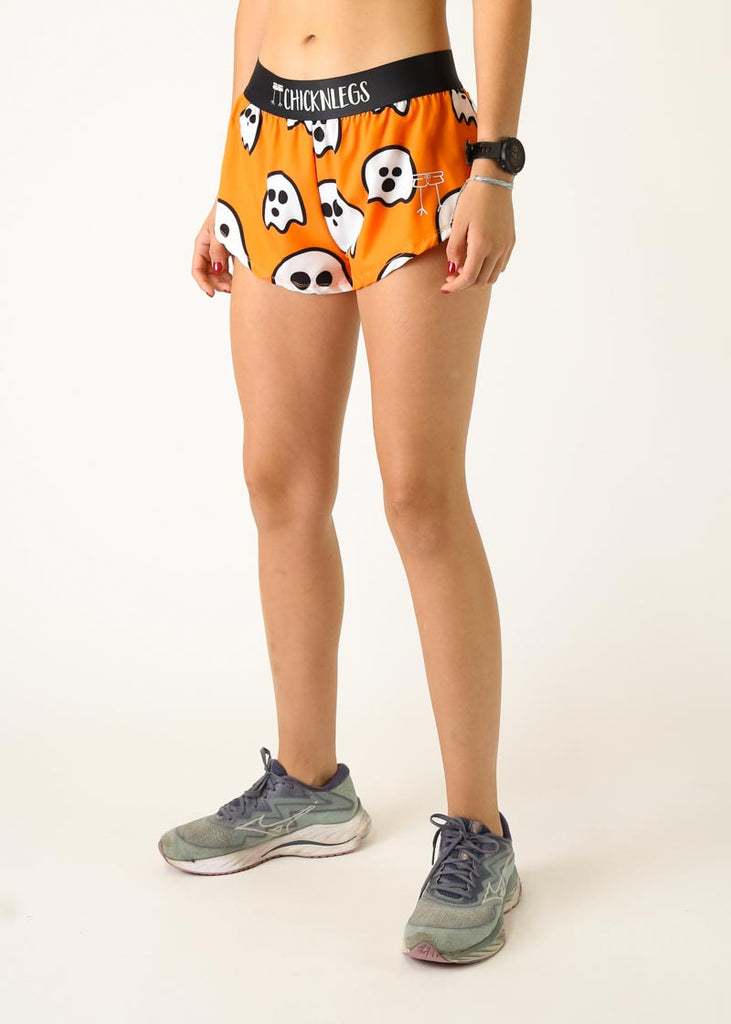 The model is a runner wearing Chicknlegs women's 1.5 inch split running shorts in the Ghosts design, facing left.
