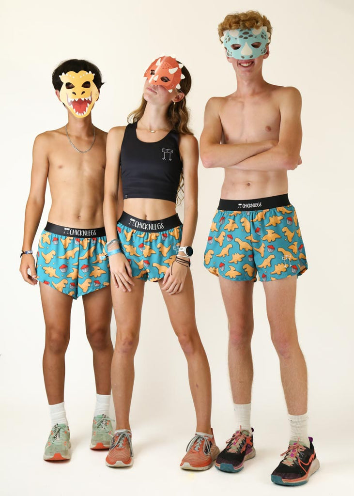 Group photo of models wearing Chicknlegs in women's 1.5 inch, men's 2 inch, men's 4 inch in dino nugget running split shorts wearing dino masks.