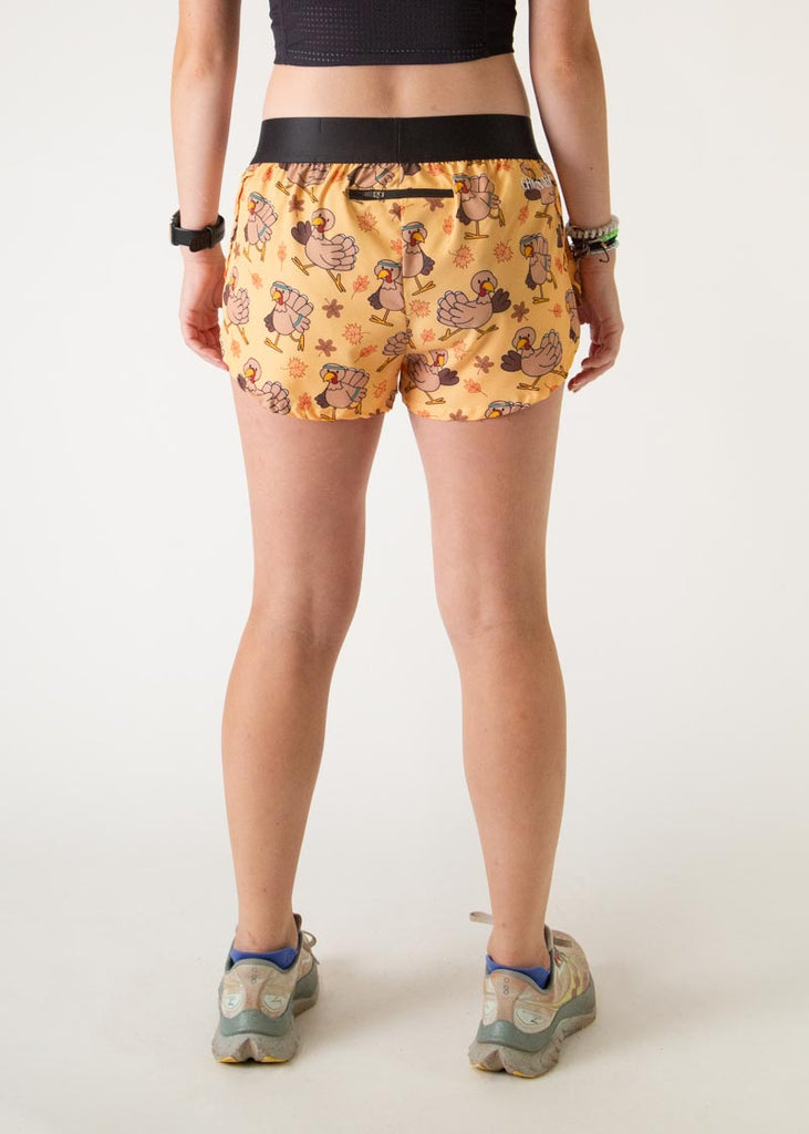 The model is a runner who is wearing Chicknlegs women's 1.5" split running shorts in the pardoned turkey design, facing away from the camera to show the back of the shorts.
