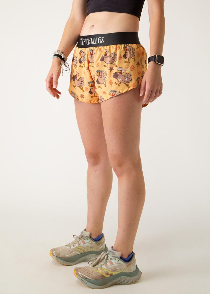 The model is a runner who is wearing Chicknlegs women's 1.5" split running shorts in the pardoned turkey design, facing left.
