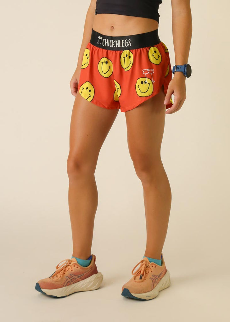 Model is wearing Chicknlegs women's 1.5 inch split running shorts in the smiley design facing left for side view.
