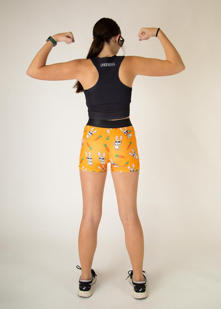 Runner is wearing ChicknLegs in the women's compression spandex in the bad bunny design, facing away from the camera. The print has white bunnys on it with sunglasses and carrots. 