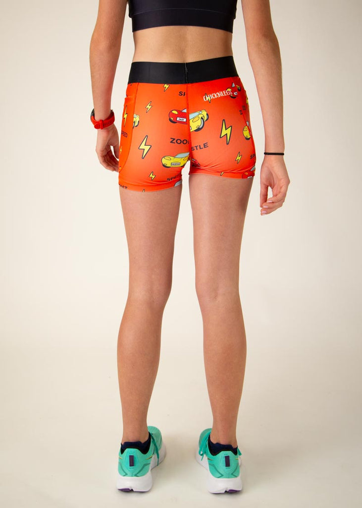 The model is a runner who is wearing Chicknlegs women's 3 in compression spandex shorts with pockets, in the cars design, facing away from the camera to show the back of the compression shorts.