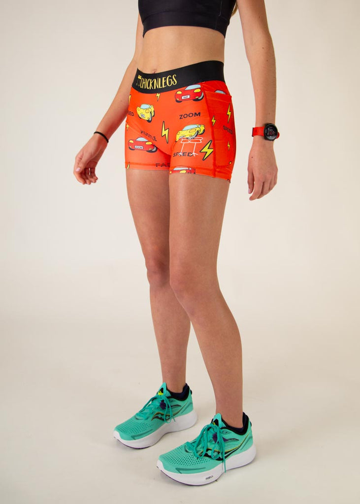 The model is a runner who is wearing Chicknlegs women's 3 in compression spandex shorts with pockets, in the cars design, facing left.