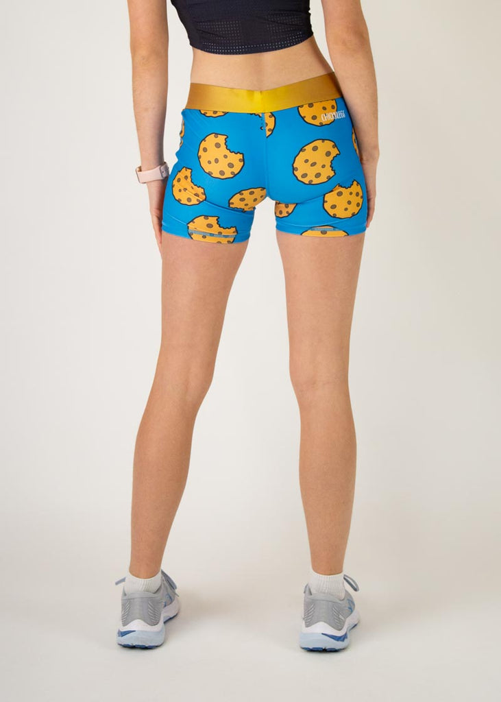The model is a runner who is wearing Chicknlegs women's 3" compression shorts in the cookies design, facing away from the camera to show the back of the compression.