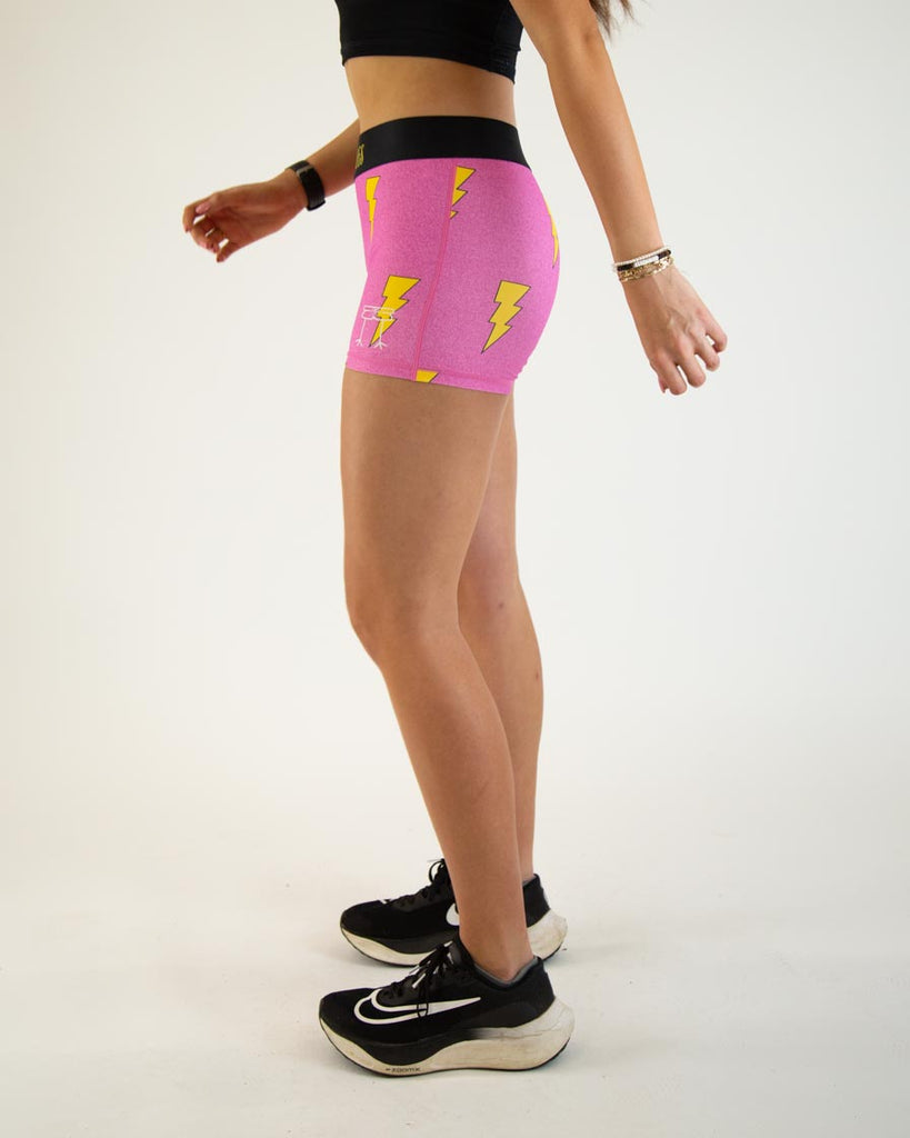 Runner is wearing ChicknLegs women's 3 in compression spandex with no pockets. The print is the hot pink bolts design with neon pink background and yellow lighting.