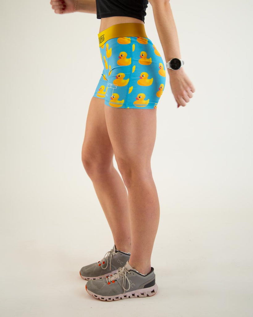 Runner is wearing ChicknLegs in the women's 3 in compression spandex shorts with no pockets. The print has yellow rubber ducky on it with a blue background and yellow waistband.