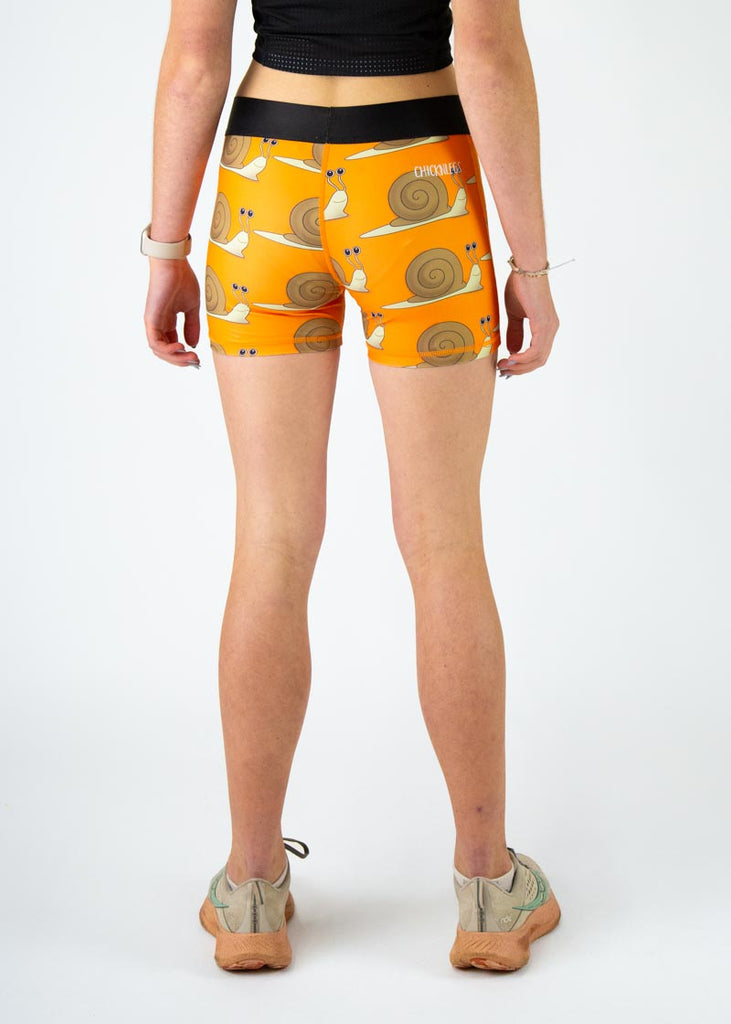 The model is a runner who is wearing Chicknlegs in the women's 3" compression shorts in the snails design, facing away from the camera to show the back of the compression.