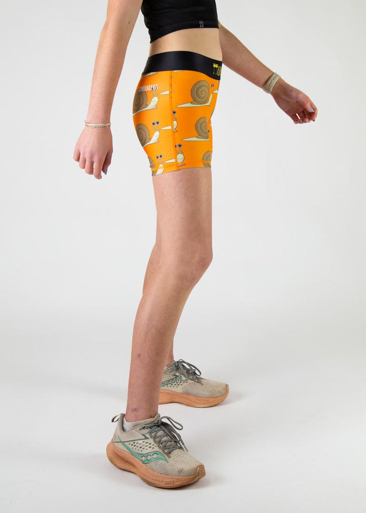 The model is a runner who is wearing Chicknlegs in the women's 3" compression shorts in the snails design, facing right.