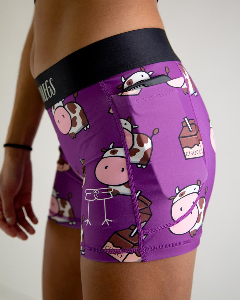 Runner is wearing ChicknLegs in the women's 3 in compression spandex shorts with pocket in the choccy cows design. The image shows a phone in the pocket as a close up.