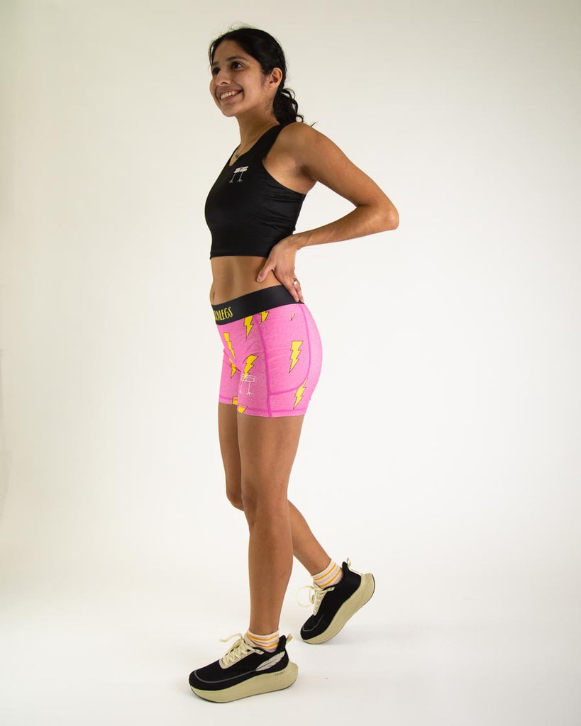 Runner is wearing ChicknLegs in the women's 3 in compression spandex with pockets shorts in the hot pink bolts design. The print has yellow lightning bolts on it with a hot neon pink background.