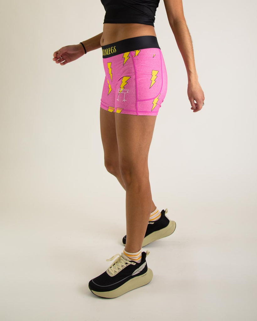 Runner is wearing ChicknLegs in the women's 3 in compression spandex with pockets shorts in the hot pink bolts design. The print has yellow lightning bolts on it with a hot neon pink background great for speedy runs.