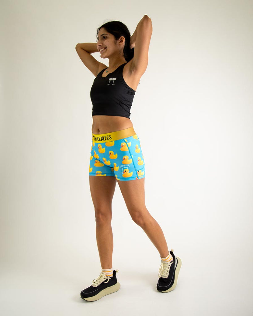 Runner is wearing ChicknLegs in the women's 3 in compression spandex shorts with pockets in the rubber ducky design. The print has yellow rubber ducks on it with a blue background. 