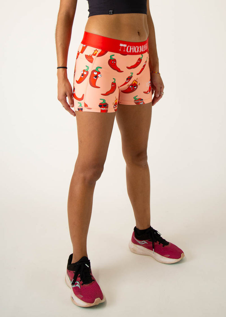 Model is a runner wearing Chicknlegs women's 3 inch compression shorts in the chili pepper design, facing right.