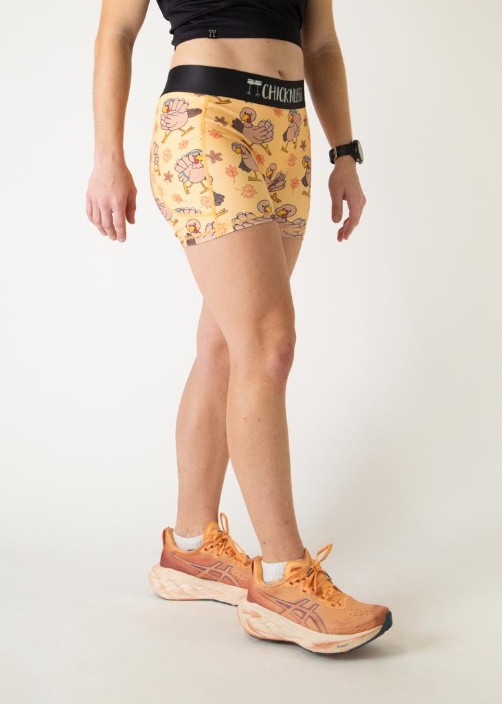 The model is a runner who is wearing Chicknlegs women's 3 inch compression shorts in the pardoned turkey design, facing right.