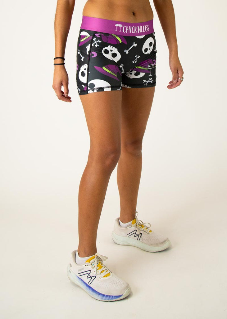 The model is a runner wearing Chicknlegs in women's 3 inch compression shorts in the skulls design, facing right.