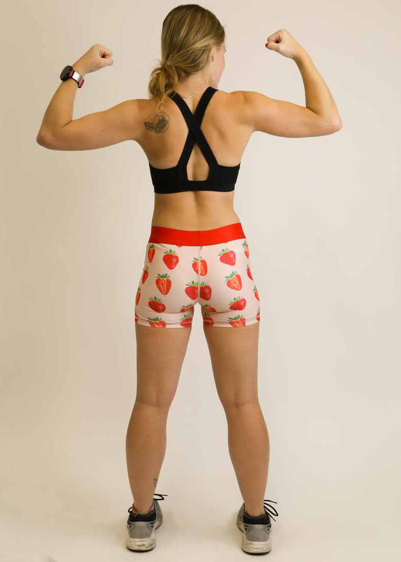Back view of runner flexing her biceps while wearing the strawberry 3 inch compression running shorts.