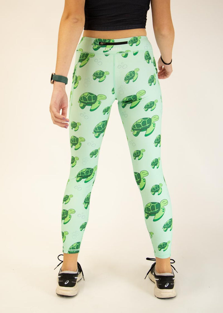 The model is a runner who is wearing Chicknlegs Women's Leggings in the Sea Turtles design. These leggings include side pockets and an adjustable drawstring at the front. The model is facing away from the camera to show the back of the leggings.