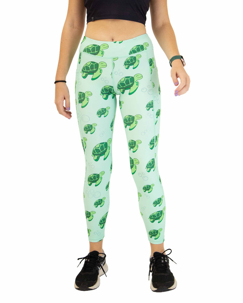 Runner is wearing ChicknLegs in the women's drawstring leggings with pockets in the sea turtles design. The print has bubbles and turtles on it that are green on a light solid green background.