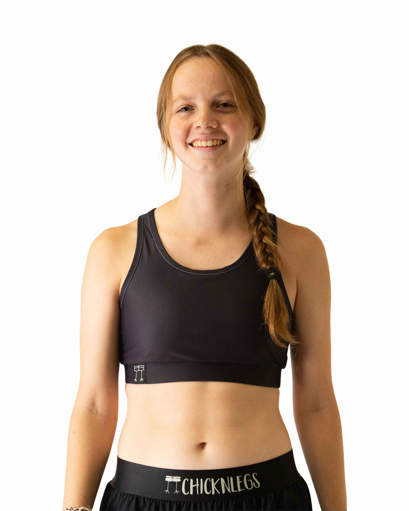 Runner is wearing ChicknLegs in the women's OG Sports Bra has a back pocket for exercise, running, workout, gym, and every day lifestyle. The print is a solid black color.