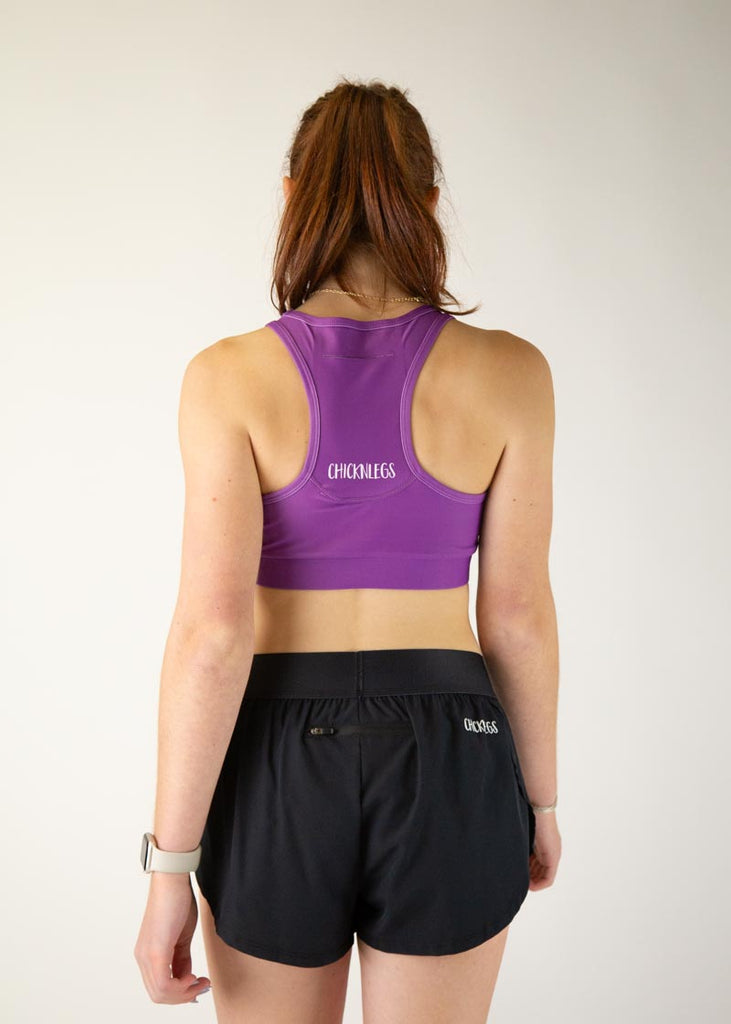 The model is a runner who is wearing Chicknlegs in thhe women's OG sports bra in the deep purple design, facing away from the camera to show the back of the sports bra.