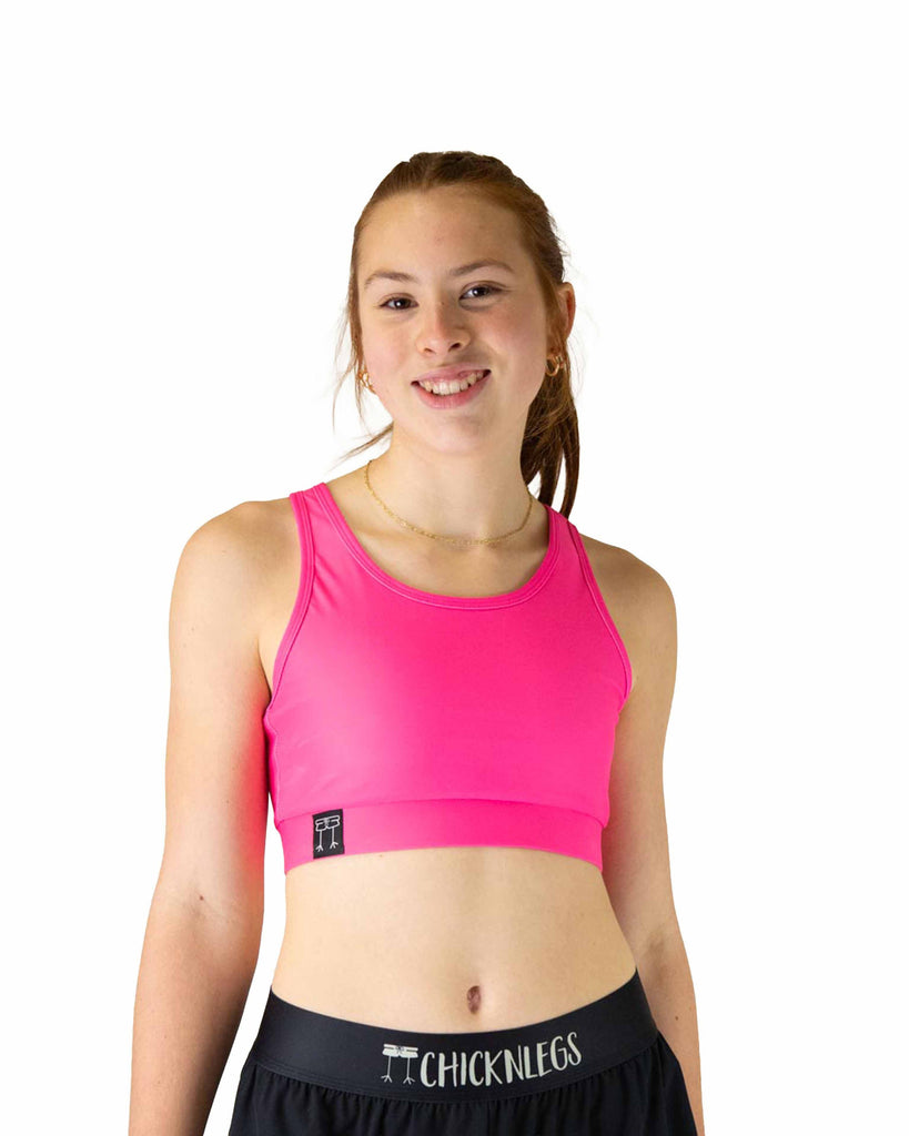 Runner is wearing ChicknLegs in the women's OG Sports Bra has a back pocket for exercise, running, workout, gym, and every day lifestyle. The print is the solid neon pink design, great for matching with the blue flamingos or for holidays such as valentines day.