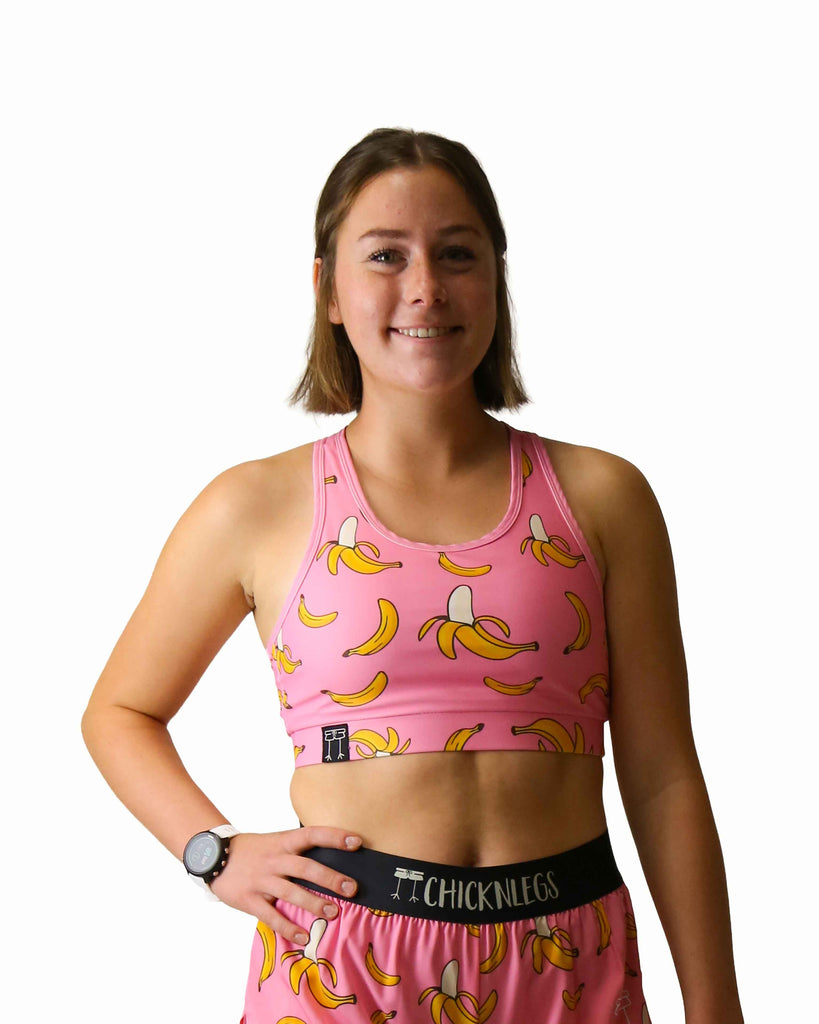 Runner is wearing ChicknLegs in the women's OG Sports Bra has a back pocket for exercise, running, workout, gym, and every day lifestyle. The print is the pink bananas which has yellow bananas on a bright pink background.