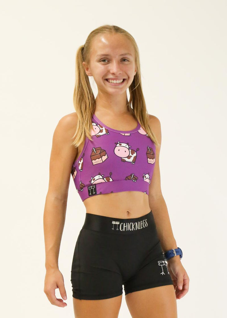 Model wearing Chicknlegs OG Sports Bra in the choccy cows design facing right for side view.