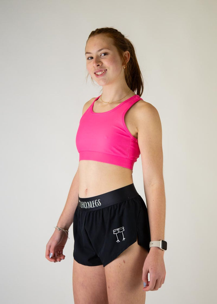 The model is a runner who is wearing Chicknlegs in the women's OG sports bra in the neon pink design, facing left.