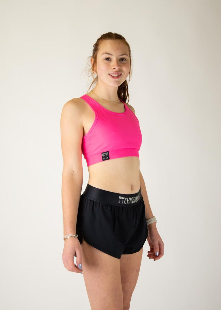 The model is a runner who is wearing Chicknlegs in the women's OG sports bra in the neon pink design, facing right.