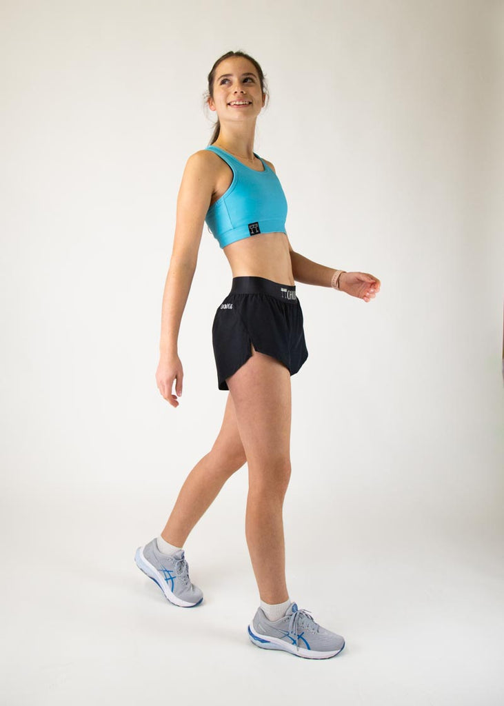 The model is a runner who is wearing Chicknlegs in the women's OG sports bra in the sky blue design, facing front while in a walking stance. A full body is shown in this image of the model.