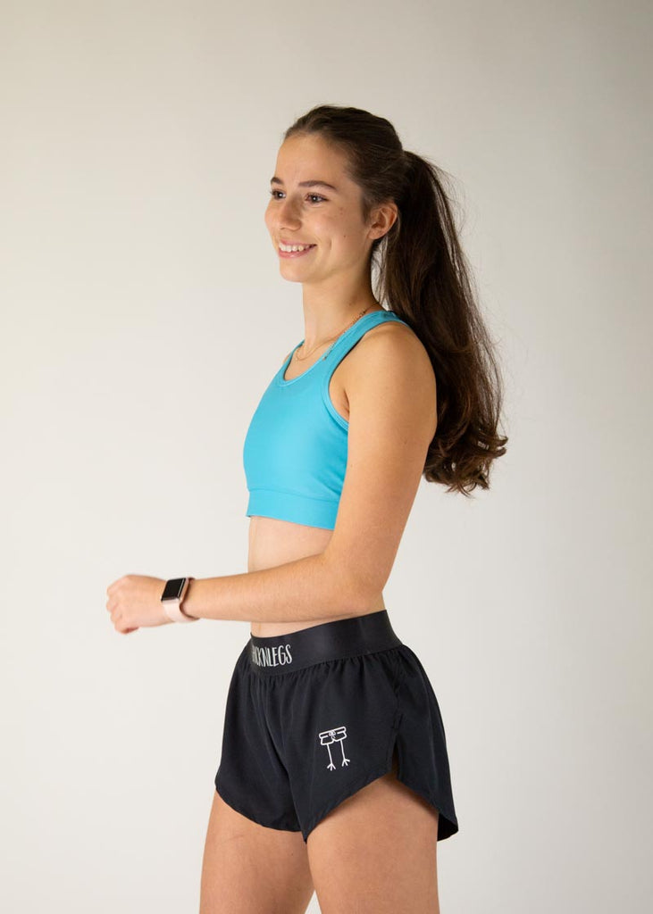 The model is a runner who is wearing Chicknlegs in the women's OG sports bra in the sky blue design, facing left.