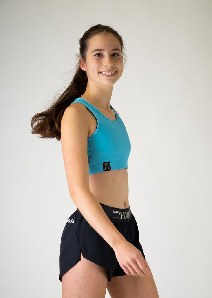 The model is a runner who is wearing Chicknlegs in the women's OG sports bra in the sky blue design, facing right.