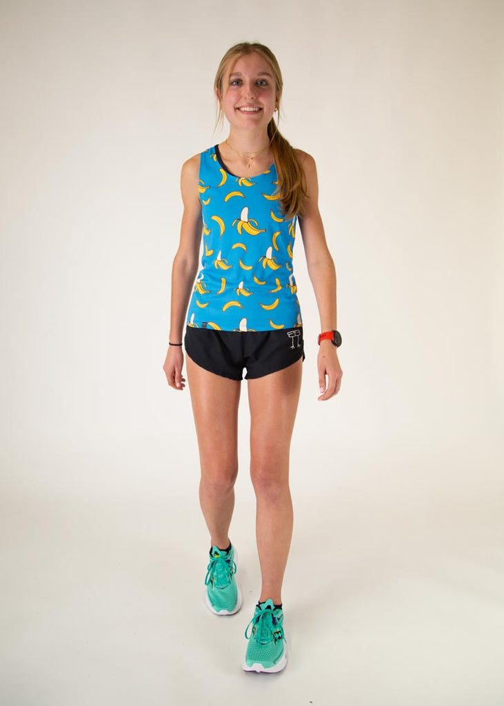 The model is a runner who is wearing Chicknlegs women's performance singlet in the blue banana design, facing front in a walking pose.