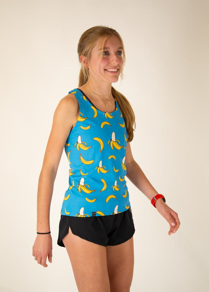 The model is a runner who is wearing Chicknlegs women's performance singlet in the blue banana design, facing right.