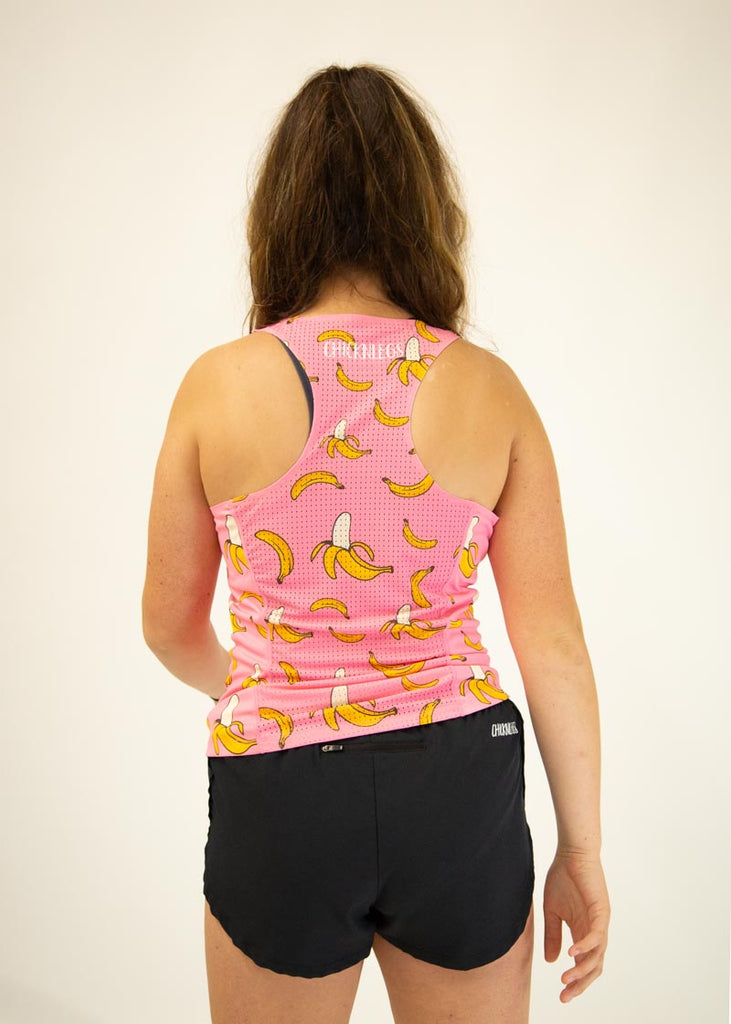 The model is a runner who is wearing Chicknlegs women's performance singlet in the pink banana design, facing  away from the camera to show the back of the singlet.