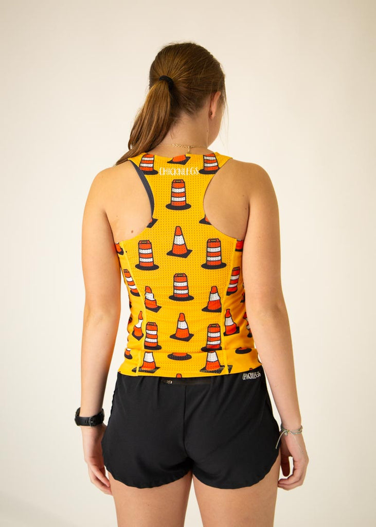The model is a runner who is wearing Chicknlegs women's performance singlet in the traffic cones design, facing away from the camera to show the back of the singlet.